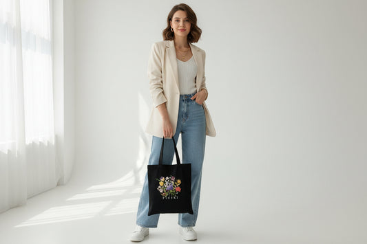 Person holding a black tote bag with floral design and 'Floral' text.